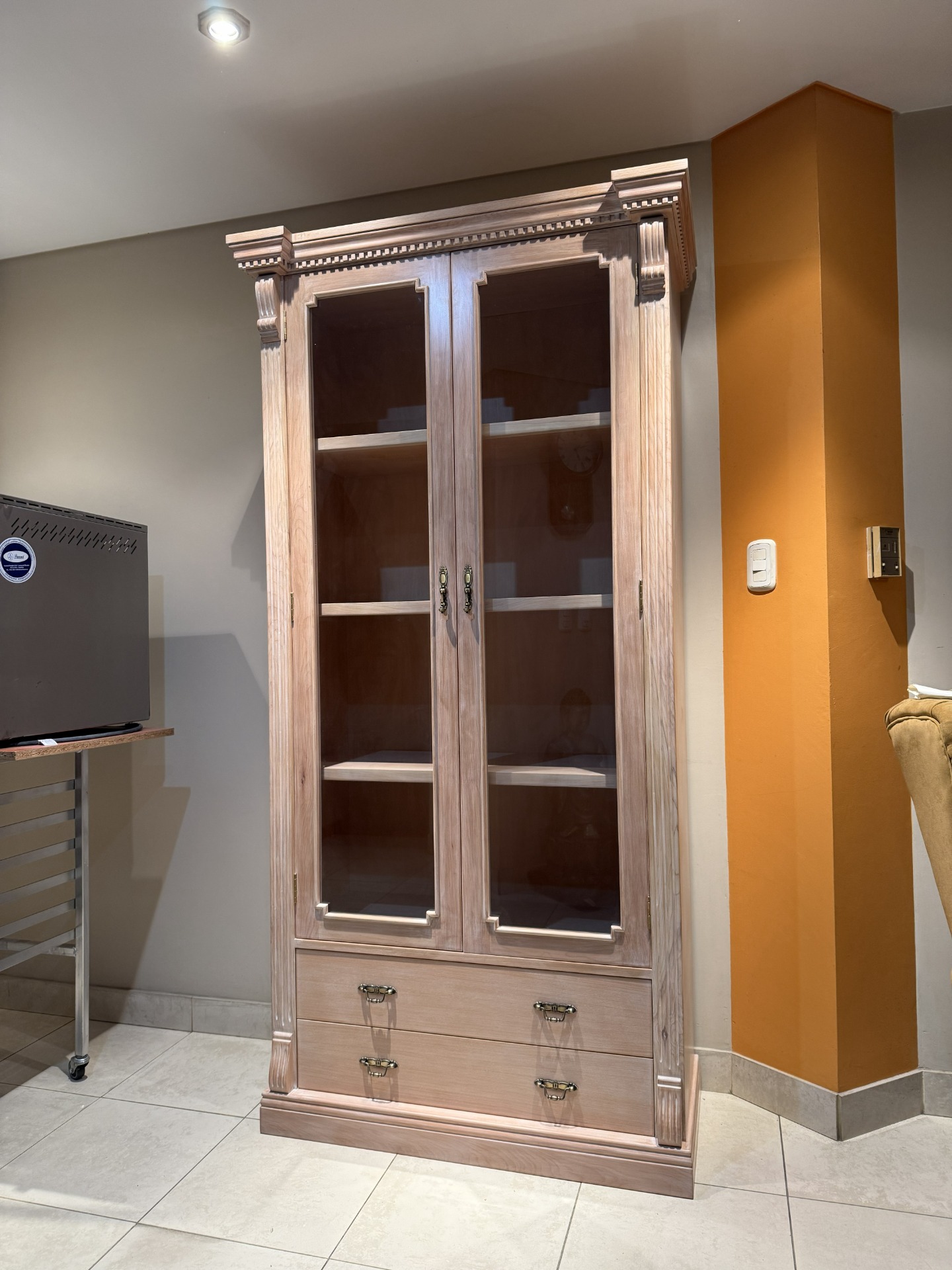 Vitrina de madera clara con puertas de vidrio, cajones inferiores 